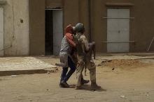 Un soldat malien porte un enfant blessé lors d'une attaque contre des soldats français le 1er juillet au Mali
