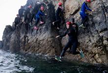 Des personnes se déplacent sur une paroi rocheuse avant de sauter dans un trou d'eau, lors d'une sortie de coasteering ou canyoning côtier, le 25 juillet 2018 à Morgat dans le Finistère