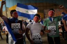 Des jeunes masqués participent à une veillée de commémoration des 100 jours de révolte contre le gouvernement de Daniel Ortega, à Managua le 26 juillet 2018