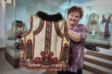 Une femme employée au musée local de la région de Bihor montre un vêtement traditionnel vieux de 100 ans, le 17 juillet 2018 à Beius, en Roumanie