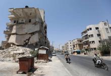 Des Syriens circulent devant des bâtiments détruits à Idleb, dans le nord-ouest de la Syrie, le 2 août 2018