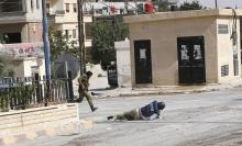 Sammy Ketz, grand reporter à l'AFP, à terre pendant des échanges de tirs dans la ville de Maaloula en Syrie, alors qu'un militaire syrien traverse en courant, le 18 septembre 2013