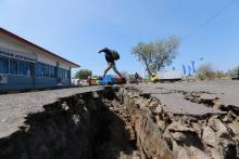 Un homme enjambe une crevasse causée par un séisme à Mataram, sur l'île indonésienne de Lombok, le 20 août 2018
