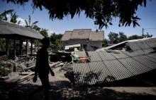 Un homme marche près d'un bâtiment effondré dans le village de Sugian sur l'île indonésienne de Lombok secouée par une série de séismes, le 20 août 2018