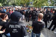 Des policiers surveillent des citoyens réunis dans les rues de Chemnitz, le 26 août 2018, en mémoire d'un Allemand de 35 ans tué lors d'une bagarre