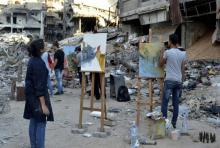 Un groupe d'étudiants des Beaux-Arts peignent, le 15 août 2018, en plein coeur du quartier populaire de Yarmouk à Damas, dévasté par des années de combats.