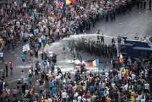 Les gendarmes roumaines utilisent un canon à eau pour repousser la foule venue manifester devant le siège du gouvernement à Bucarest, le 10 août 2018