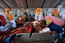 Des équipes de secours prennent en charge des blessés dans un hôpital de fortune, le 6 août 2018 à Mataram, après un séisme meurtrier sur l'île de Lombok, en Indonésie