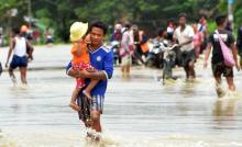 Des Birmans poussent une voiture sur une route inondée à Bago, le 29 août 2018