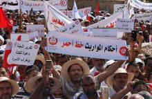 Un manifestant en Tunisie brandit un coran et une pancarte sur laquelle on peut lire "les règles de l'héritage sont une ligne rouge", lors d'un rassemblement de milliers de personnes dénonçant des réf