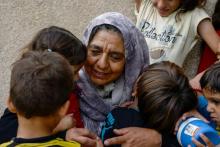 Sana Ibrahim (C), 61 ans, s'occupe de ses petits-enfants orphelins dans sa maison à Mossoul, dans le nord de l'Irak, le 14 août 2018