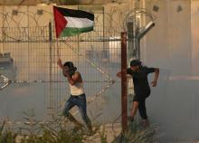 Un manifestant arbore un drapeau palestinien et court à travers les gaz lacrymogènes tirés par des soldats israéliens lors d'une protestation au passage d'Erez entre la bande de Gaza et Israël, le 4 s