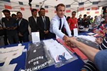 Le président Emmanuel Macron serre la main d'un visiteur devant un stand de produits dérivés de l'Elysée lors des Journées du patrimoine, le 15 septembre 2018 à Paris