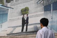 Un homme passe devant une photographie géante de la poignée de main entre le président sud-coréen Moon Jae-in et le dirigeant nord-coréen Kim Jong Un lors d'un précédent sommet, à l'hôtel de ville de 