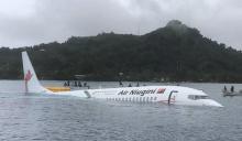 Des bateaux de sauveteurs s'approchent d'un avion de la compagnie Air Niugini qui a plongé dans un lagon après avoir raté son atterrissage, le 28 septembre 2018 sur l'île de Weno, en Micronésie