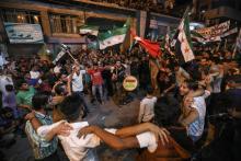 Des Syriens dansent et chantent le 17 septembre 2018, pendant que d'autres agitent des drapeaux de la Turquie et de l'opposition syrienne, lors d'une manifestation contre le gouvernement à Binnich, da