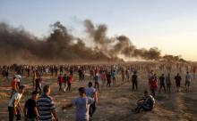 Des manifestants palestiniens se réunissent pour une manifestation le long de la frontière entre Israël et la bande de Gaza, le 21 septembre 2018, alors que de la fumée s'élève depuis des pneus en feu