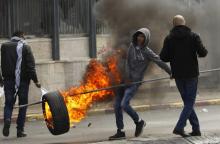 Un jeune Palestinien transporte un pneu en feu durant des heurts avec les forces de sécurité israéliennes, le 27 décembre 2017 à Bethléem, en Cisjordanie occupée