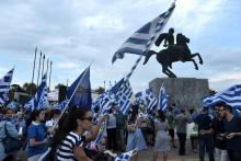 Des manifestants grecs brandissent le drapeau de leur pays près d'une statue d'Alexandre le Grand à Thessalonique le 8 septembre 2018.
