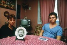 Christine et Jean-Marie Villemin, les parents du petit Grégory, assis dans leur salle à manger devant un portrait de leur fils, le 23 novembre 1984