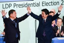 Le Premier ministre japonais Shinzo Abe (D) après sa réélection à la tête de son Parti libéral-démocrate, aux côtés de son rival Shigeru Ishiba, à Tokyo le 20 septembre 2018