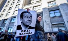 Un manifestant brandit une photo du Premier ministre russe Dmitri Medvedev sous laquelle on peut lire "Ennemi du peuple" au cours d'un rassemblement contre la réforme des retraites, à Moscou le 26 sep