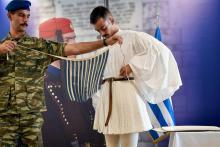l'Evzone Christos Lialis (d) reçoit l'aide d'un camarade pour fixer sa "fustanelle", la jupe plissé blanche de son corps d'élite, le 20 septembre 2018 à Athènes