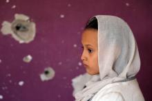 Une jeune fille yéménite, devant un mur criblée de balles, à Taez (Yémen), le 30 septembre 2018
