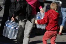 Une femme et un enfant transportent des bouteilles d'eau distribuées par les collectivités locales, après que l'eau courant ait été rendue impropre à la consommation à Yvetot, en Seine-Maritime, le 20
