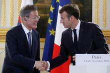 French President Emmanuel Macron (R) shakes hands with South Korean President Moon Jae-in during a press conference at the Elysee Palace in Paris on October 15, 2018.