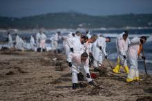 Des personnels nettoient les boulettes d'hydrocarbures déversées dans la mer après la collision de deux navires au large de la Corse, le 18 octobre 2018 sur la plage de Ramatuelle, dans le Var