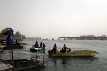 Des Syriens empruntent le fleuve de l'Euphrate le 15 octobre 2018 pour se rendre à Raqa ou sortir de cette ville du nord syrien, avec en arrière plan l'un des ponts détruits pendant l'offensive qui a 