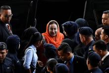 Rosmah Mansor (centre), l'épouse de l'ancien Premier ministre malaisien, est escortée par la police à son arrivée au tribunal à Kuala Lumpur le 4 octobre 2018