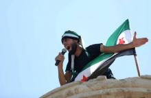Un manifestant arborant le drapeau de l'oppsoition syrienne lance des slogans dans un micro lors d'une protestation contre le régime dans la ville rebelle de Maaret al-Noomane, dans la province d'Idle