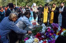 Des gens déposent des fleurs lors d'une messe à Kertch, en Crimée, le 18 octobre 2018, au lendemain de la tuerie dans un lycée technique qui a fait 20 morts