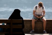 Une femme en niqab, assise sur un banc devant le lac de Zell am See, le 6 août 2018 en Autriche