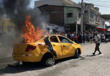 Un taxi incendié par une foule en colère qui a lynché trois personnes se trouvant à bord, accusées à tort de vol d'enfants, à Posorja en Equateur le 16 octobre 2018