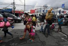 Des migrants honduriens en route pour les Etats-Unis mangent sur le trottoir à Guatemala, le 17 octobre 2018