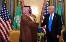 Le président américain Donald Trump (D) brandit un panneau sur des ventes dans le secteur de la Défense à l'occasion d'un entretien avec le prince héritier saoudien, Mohammed Ben Salmane, le 20 mars 2