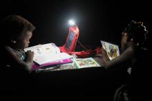 Des écolières ivoiriennes font leurs devoirs grâce à une lampe alimentée par la batterie solaire de leur cartable, le 16 septembre à Rubino, en Côte d'Ivoire