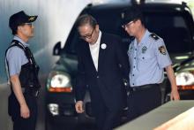 L'ex-président sud-coréen Lee Myung-bak (c), escorté par des policiers, arrive au tribunal de Séoul pour son procès, le 6 septembre 2018
