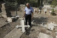 Le père Antonio Scodo, responsable de l'église du monastère salésien de Beit Jamal dans le centre d'Israël, se tient le 18 octobre 2018 devant les croix renversées du cimetière de ce monastère, situé 