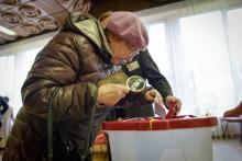 Une vieille dame dépose son bulletin dans l'urne à l'occasion des législatives lettones du 6 octobre 2018.
