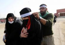 Un pèlerin chiite attache un bandeau sur le front d'une pèlerine lors de la marche d'Arbaïn, au poste de frontière de Mehran, en Iran, le 28 octobre 2018