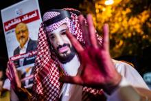 Un manifestant, les mains rougies et portant un masque à l'effigie du prince héritier saoudien Mohammed Ben Salmane, près d'une photo du journaliste Jamal Kashoggi lors d'une manifestation devant le c