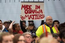 Une femme brandit une pancarte à l'usine General Motors d'Oshawa (Ontario), le 26 novembre 2018, lors d'une conférence de presse avec les syndicats