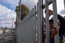 Des migrants d'Amérique centrale espérant pouvoir se rendre aux Etats-Unis regardent à travers les grilles d'un refuge situé près de la fontière américano-mexicaine, à Tijuana au Mexique, le 22 novemb