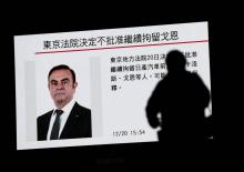 Un piéton passe devant un écran sur lequel est diffusé un programme sur le PDG de Renault et de l'Alliance Renault-Nissan Carlos Ghosn, à Tokyo, le 20 décembre 2018
