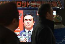 Des piétons passent devant un écran de télévision sur lequel apparaît le visage de Carlos Ghosn, ex-PDG de Nissan, le 21 décembre 2018 à Tokyo, au Japon