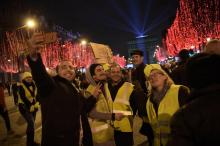 Des "gilets jaunes" font un selfie avec un badaud sur les Champs-Elysées, le 31 décembre 2018 à Paris